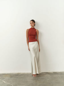 Sleek sleeveless burnt orange top featuring a high neck, fitted silhouette, and lightweight fabric, paired with a satin skirt for a chic and minimalist aesthetic.