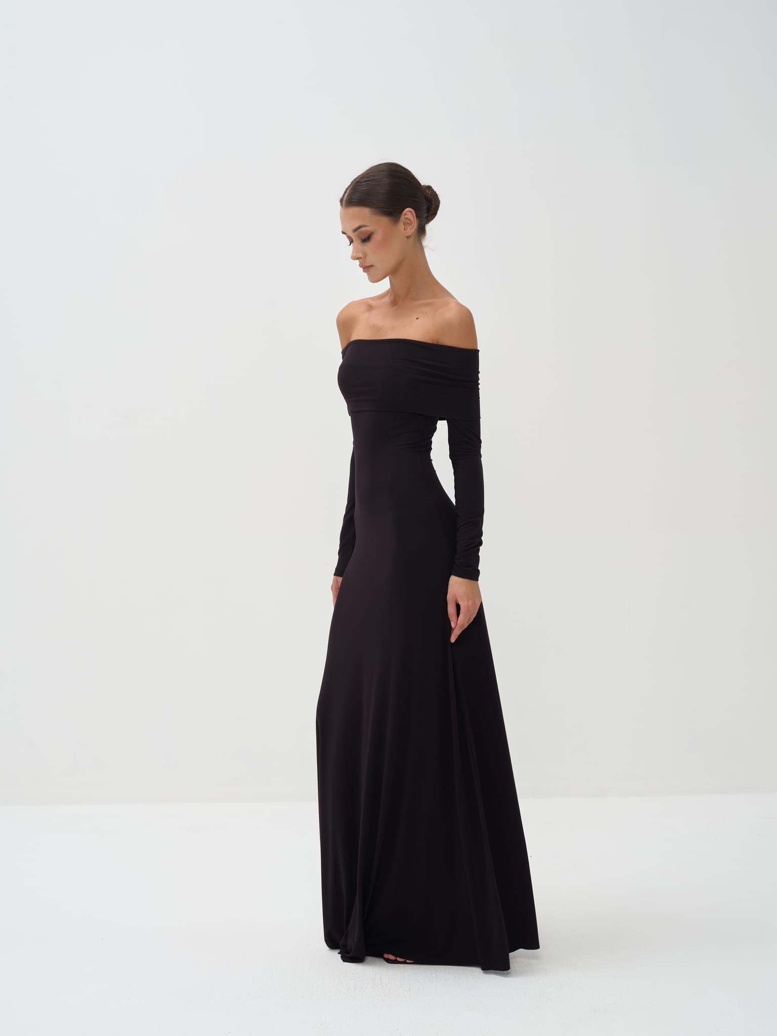 Woman wearing a black off-shoulder long-sleeve gown on a white background