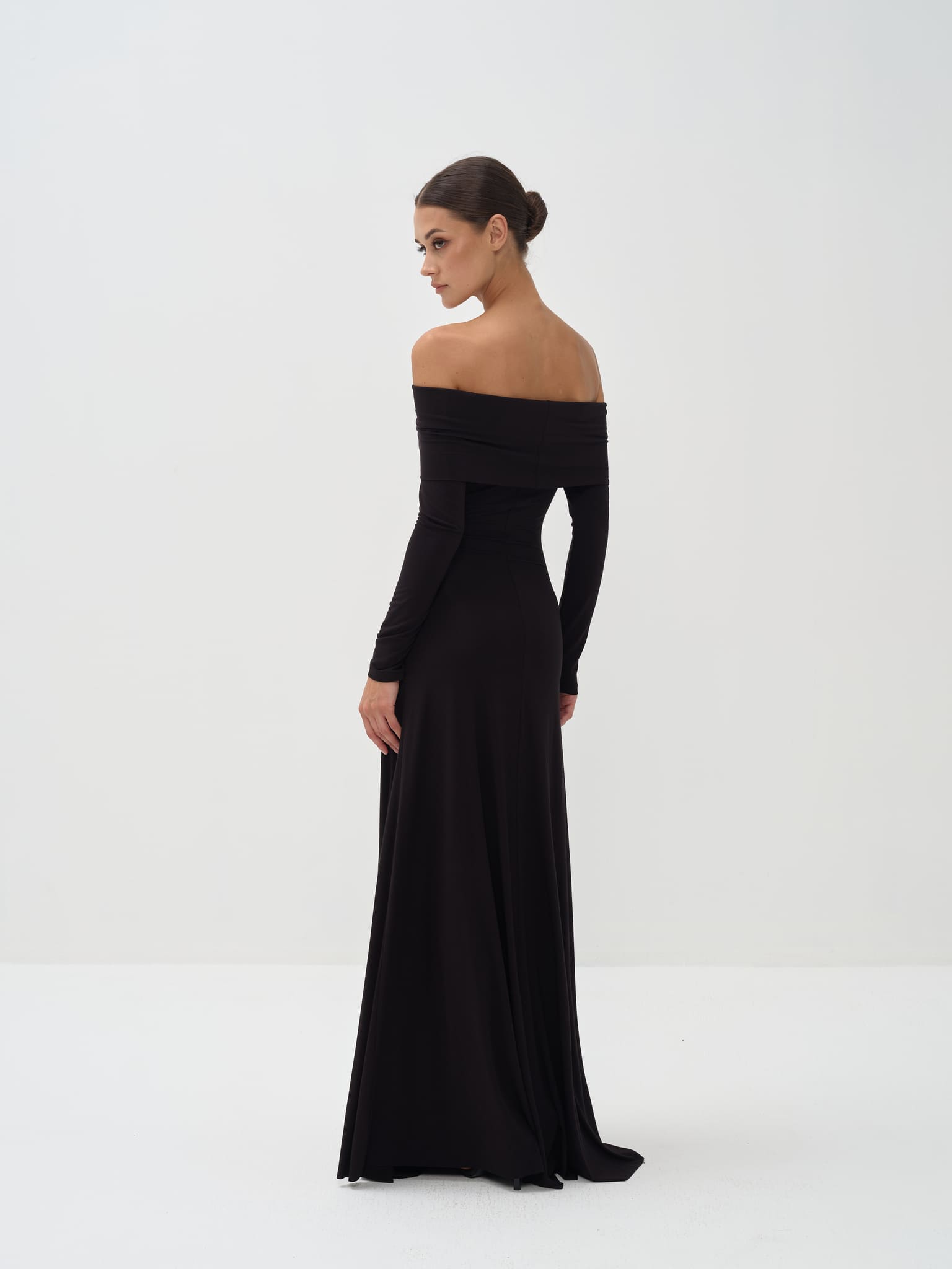 Woman wearing a black off-shoulder long-sleeve gown on a white background