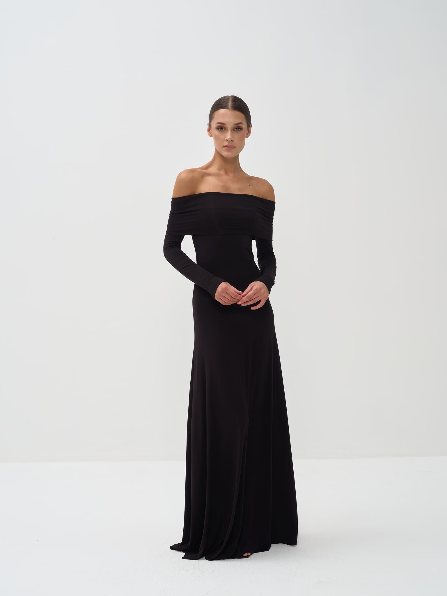 Woman wearing a black off-shoulder gown against a white background