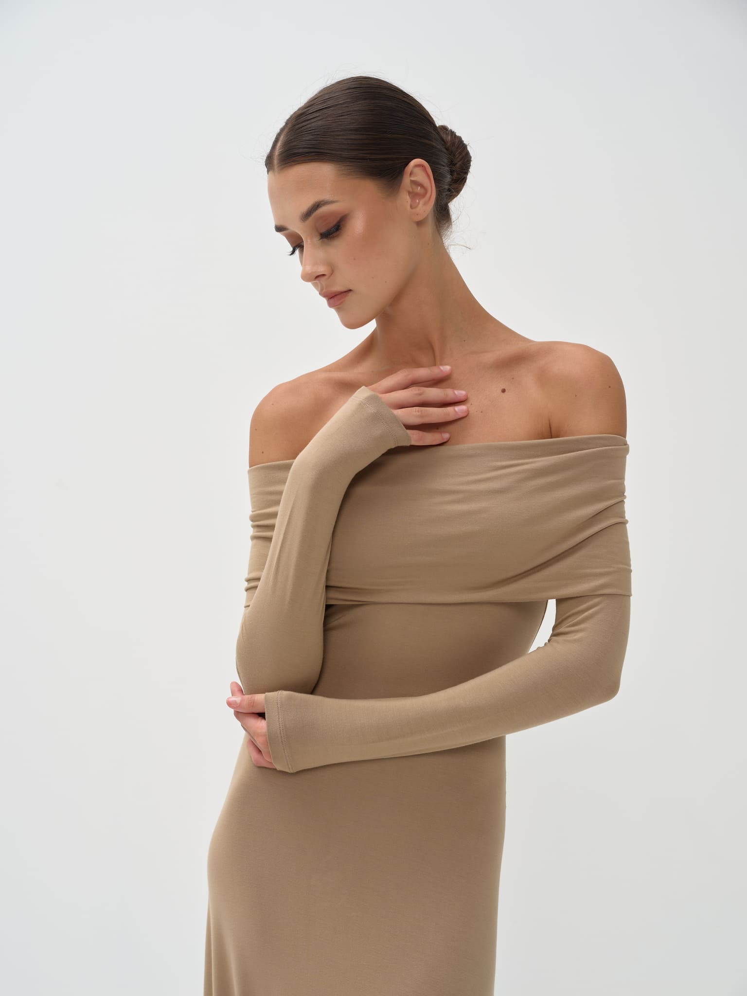 Woman wearing a beige off-shoulder dress against a white background