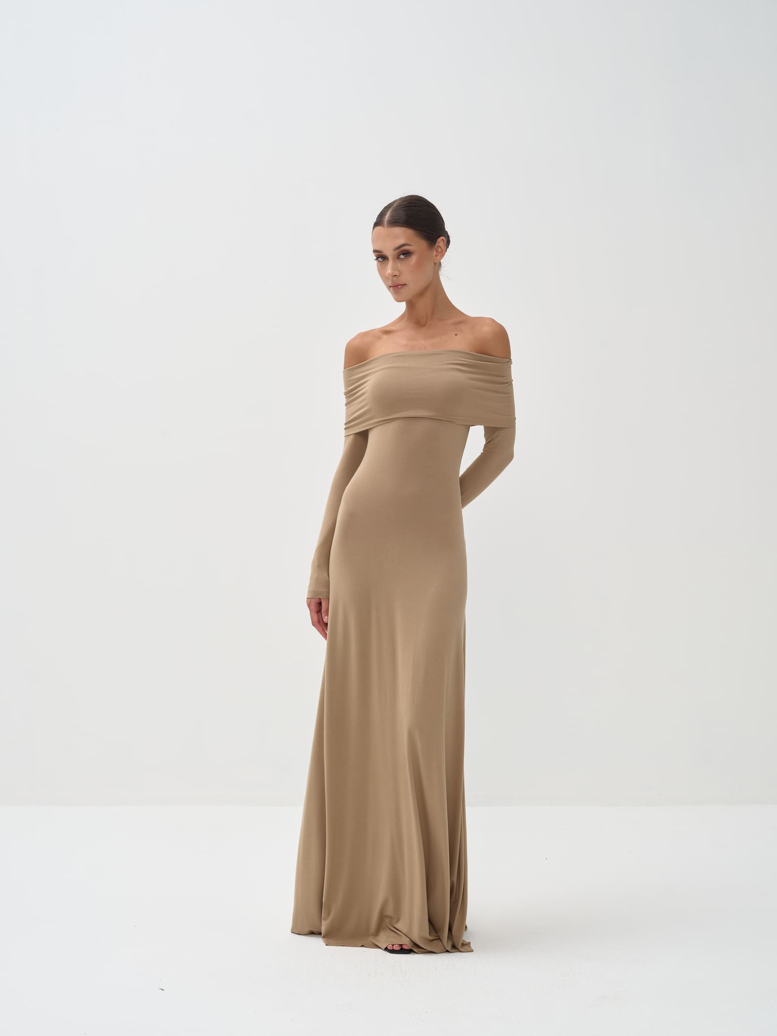 Woman wearing a beige off-shoulder gown on a white background