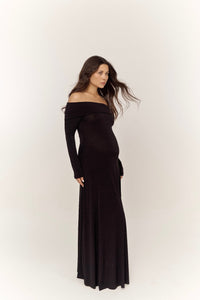 A woman with long hair wears the elegant Otis dress, standing against a plain background. The high-quality spandex fabric complements her figure as she is positioned slightly to the side, with a calm expression and her hair gently flowing.