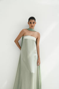 Woman wearing a strapless light green gown with a long scarf on a white background