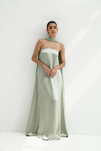 Woman wearing a strapless light green gown with a long scarf on a white background