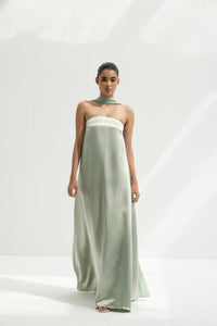 Woman wearing a strapless light green gown with a long scarf on a white background