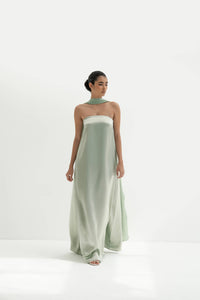 Woman wearing a strapless light green gown with a long scarf on a white background