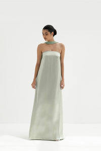 Woman wearing a strapless light green gown with a long scarf on a white background