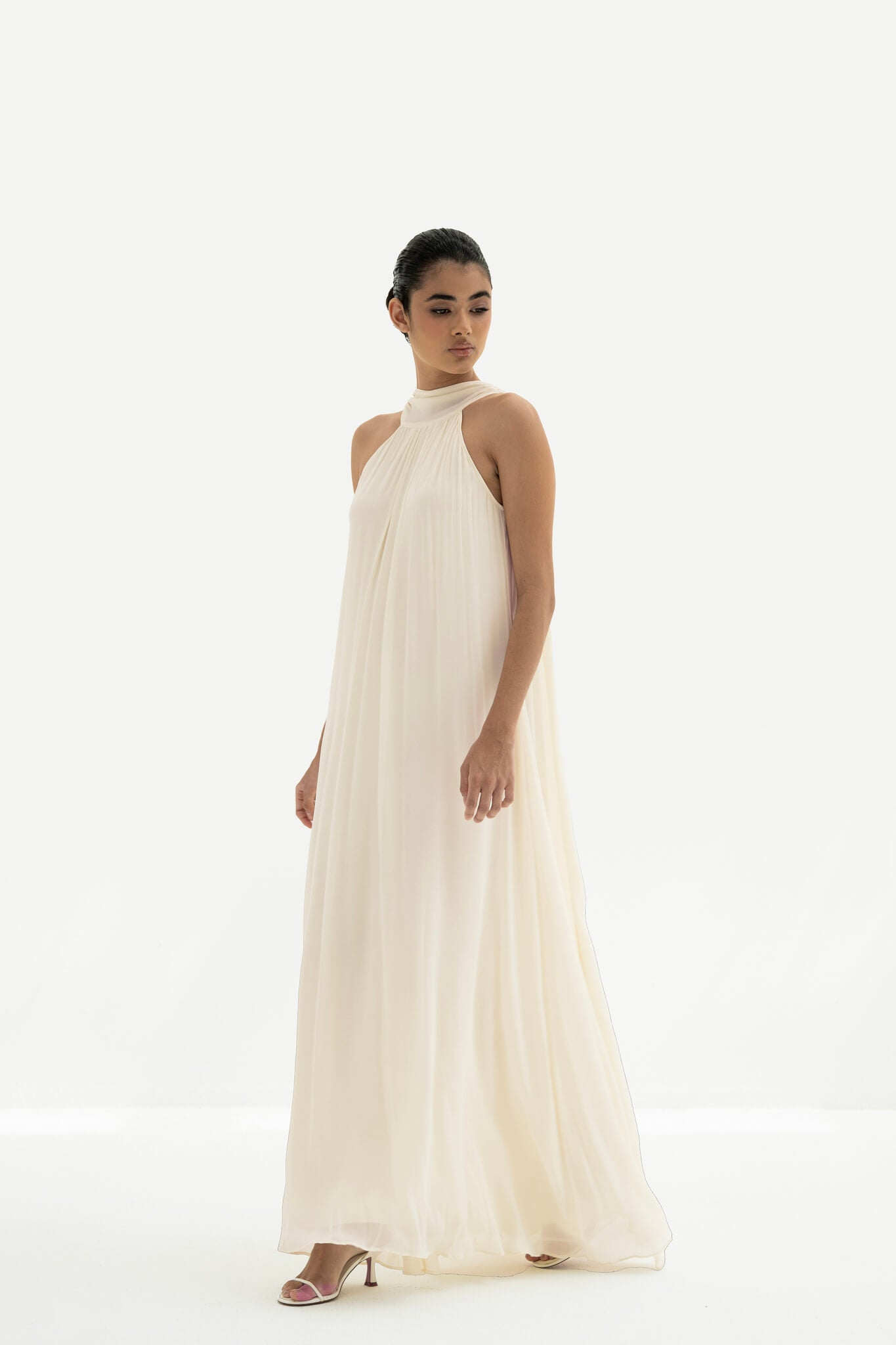 Woman wearing a long white dress against a white background