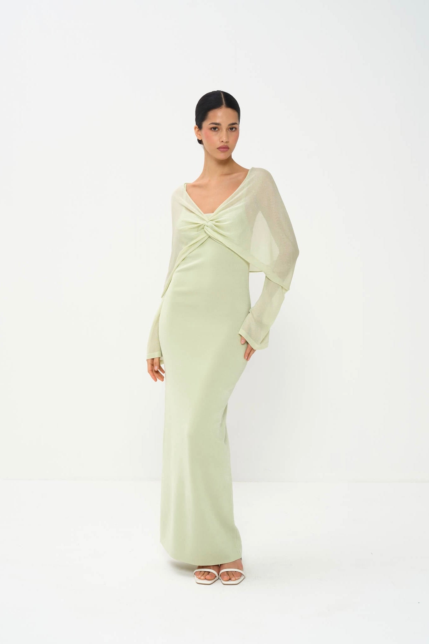 Woman wearing a light green dress with long sleeves on a white background