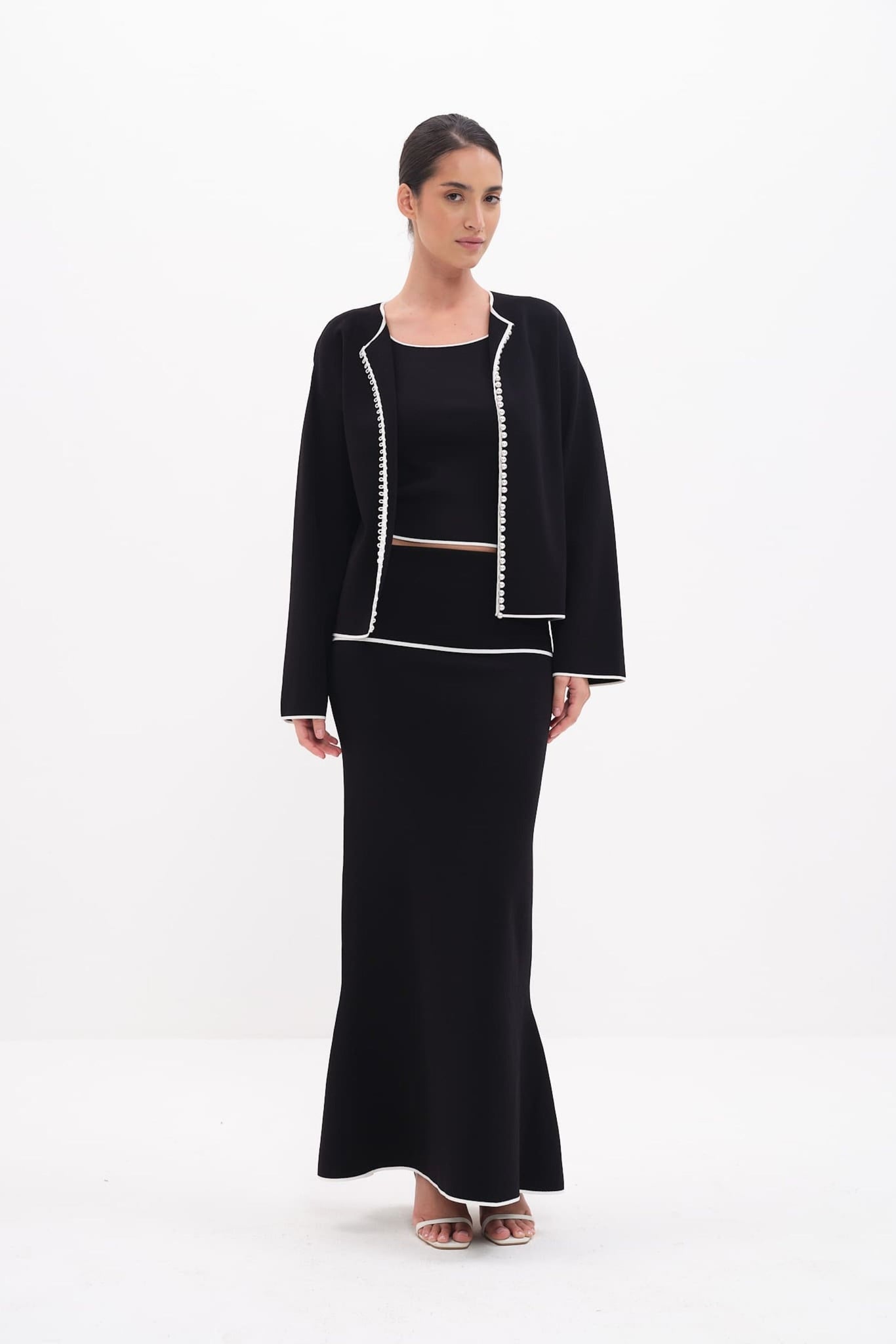 Woman wearing a black outfit with white trim on a white background