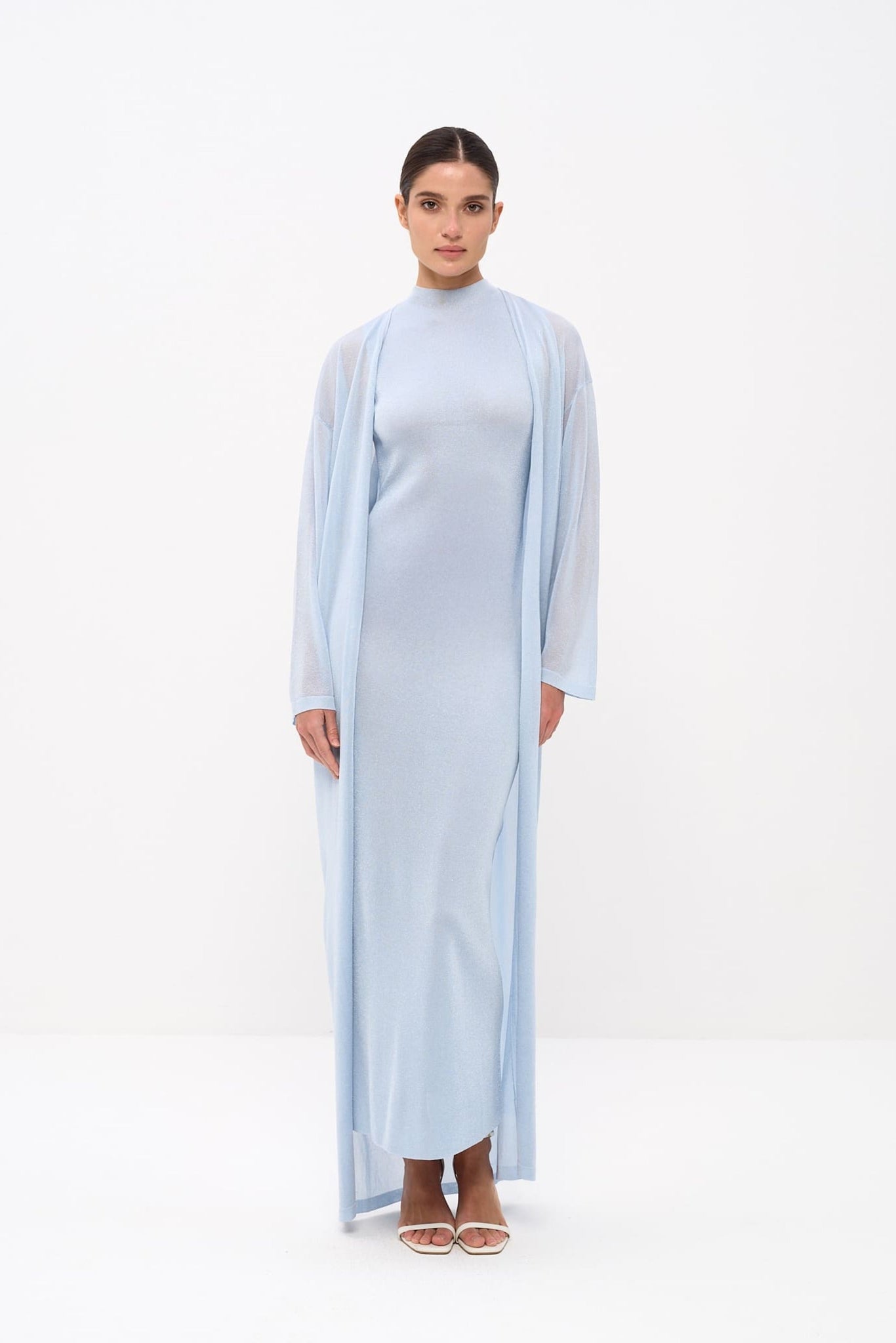Woman wearing a light blue dress with a matching long cardigan on a white background