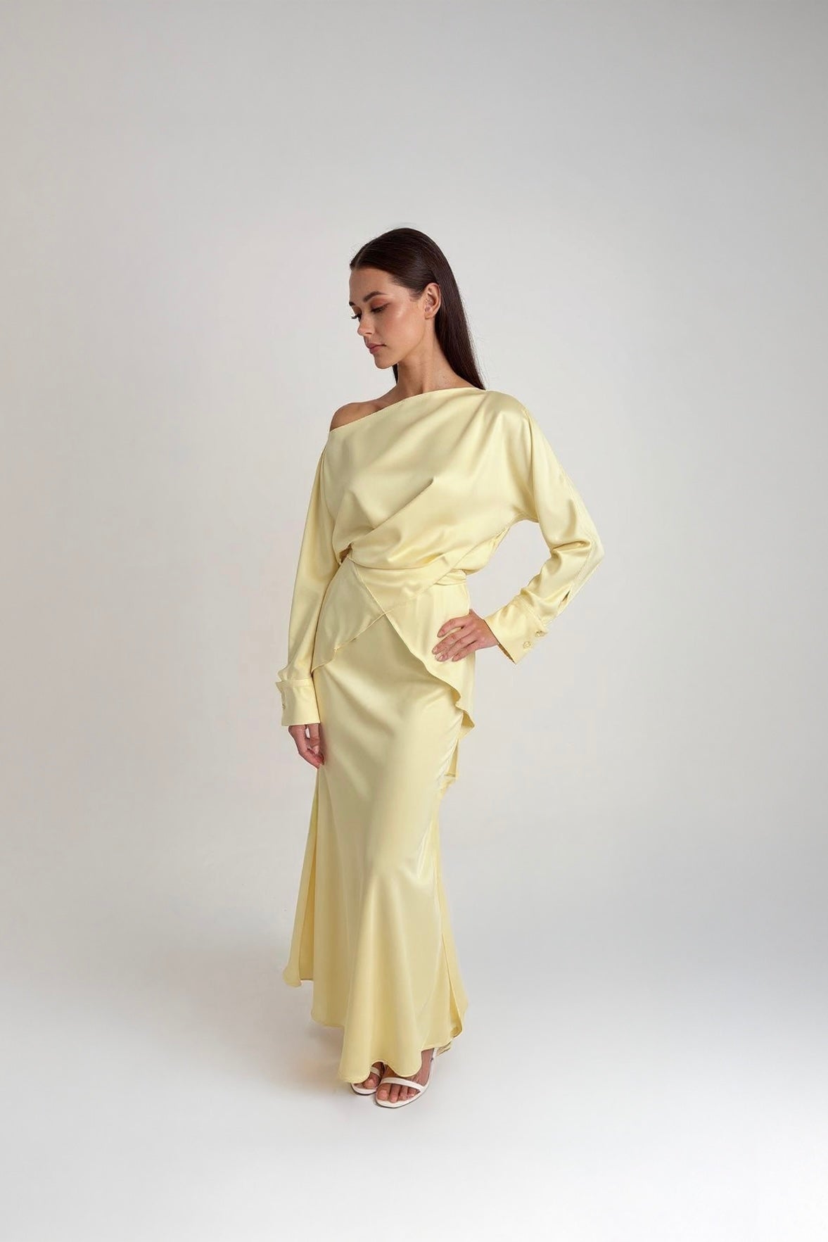 Woman wearing a light yellow off-shoulder dress on a white background