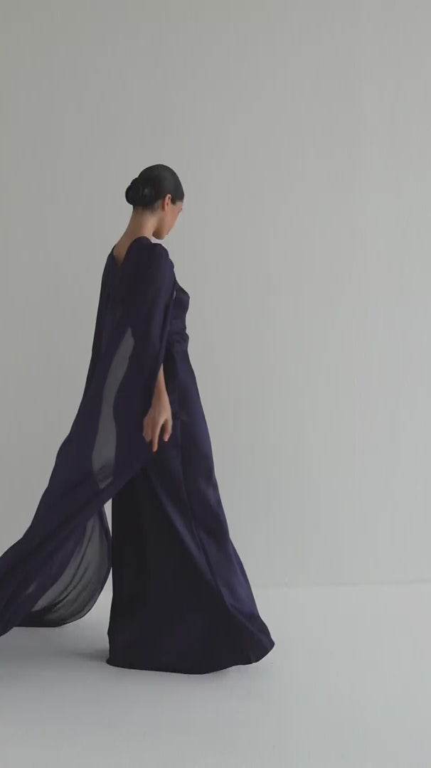 Navy blue evening gown with cape on a white background