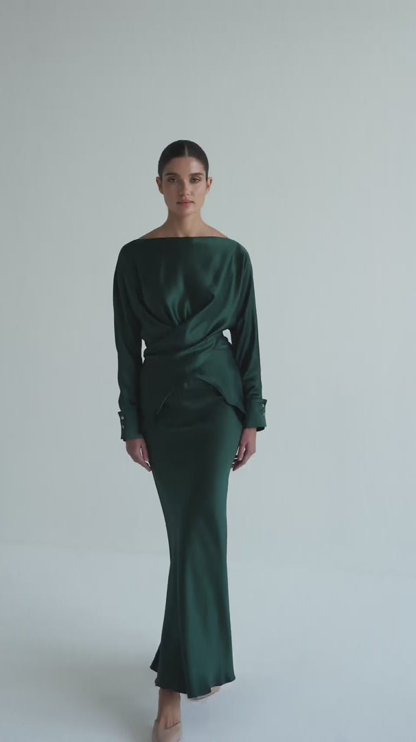 Woman wearing a dark green dress with a draped effect on a white background